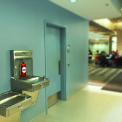 Red UIC-branded water bottle filling up in the water bottle refill station