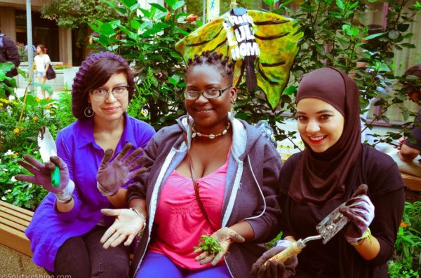 A diverse group of three Heritage Garden interns show off their dirst hands after working in the garden