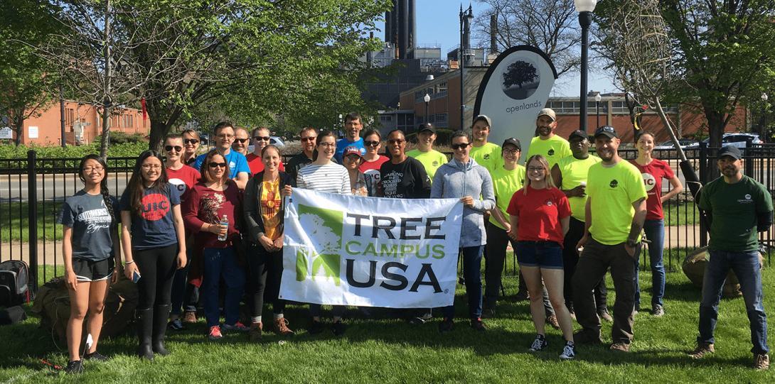 UIC staff and students hold up the Tree Campus USA banner during OpenLands tree planting event