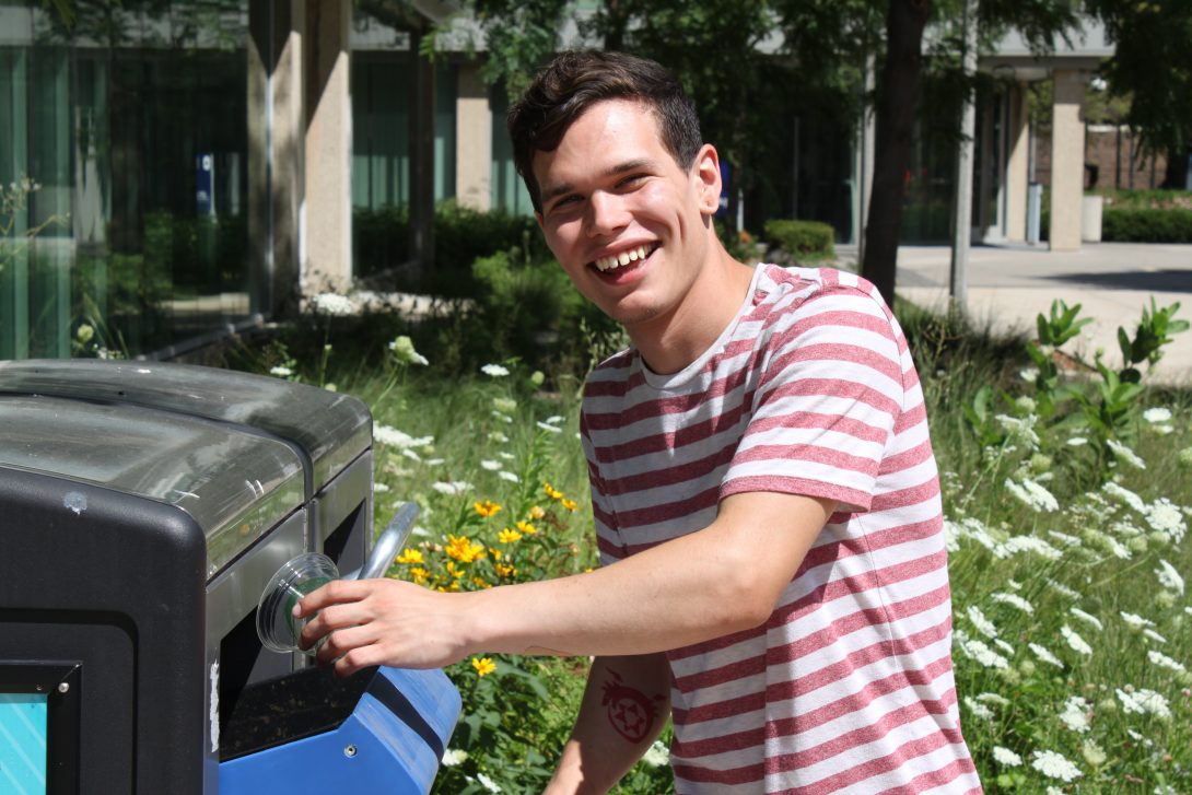 student recycling in a Bigbelly recycling station